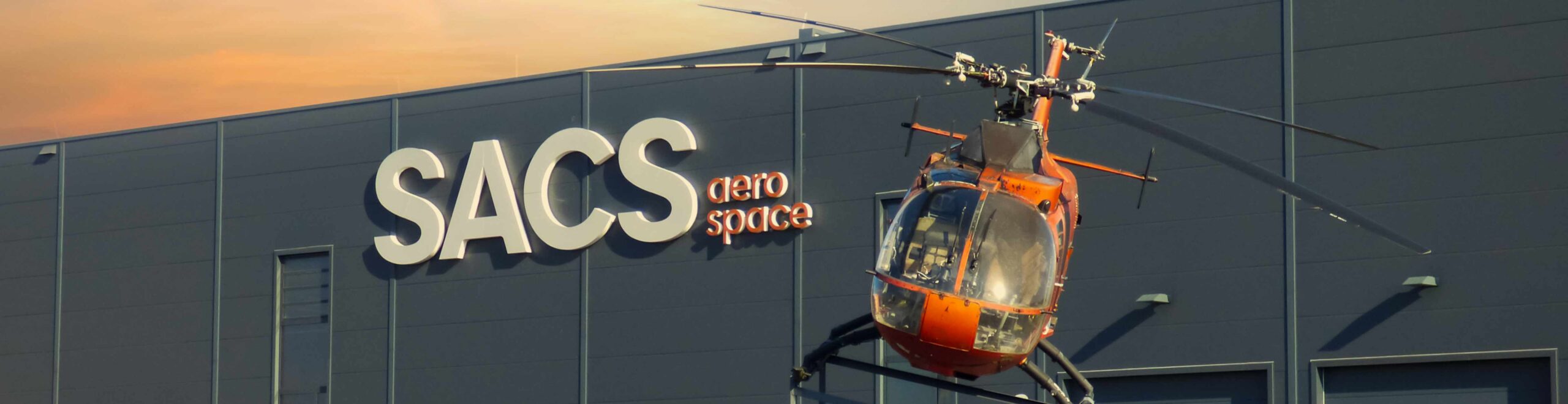 SACS_Bild_Start 02 Anblick auf die Produktionshalle und Hubschrauber vor dem Gebäude.